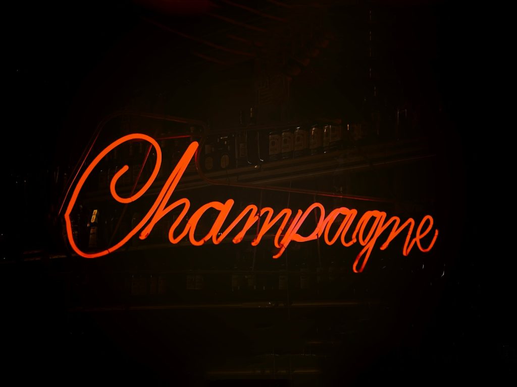 red and white UNKs neon light signage that says champagne
